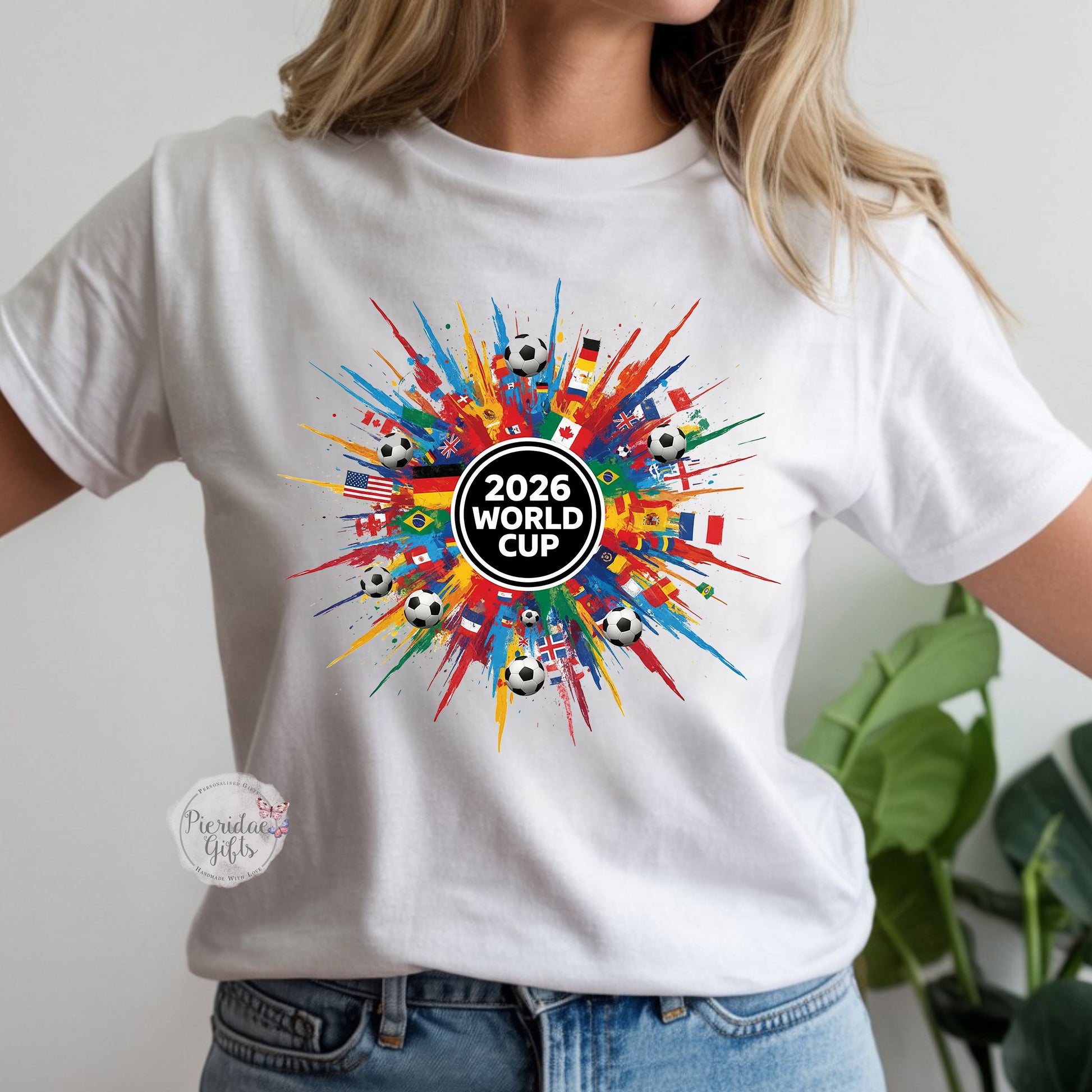 White t-shirt with 2026 World Cup design featuring colorful flags and soccer balls.