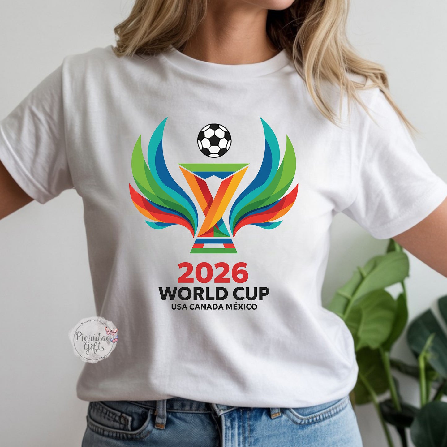 White t-shirt with 2026 World Cup logo worn by a person, with a plant in the background.
