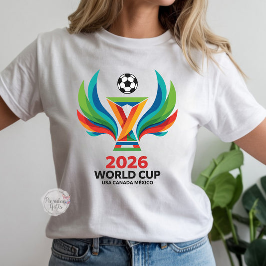 White t-shirt with 2026 World Cup logo worn by a person, with a plant in the background.